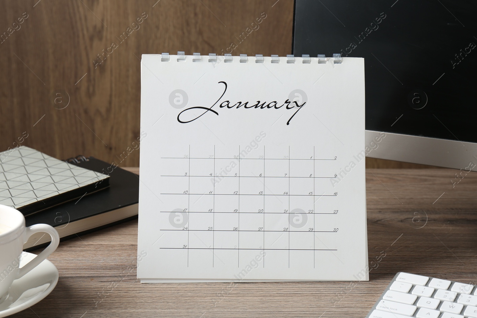 Photo of Timetable. Monthly planner, stationery and computer on wooden table