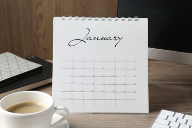 Photo of Timetable. Monthly planner, coffee, stationery and computer on wooden table