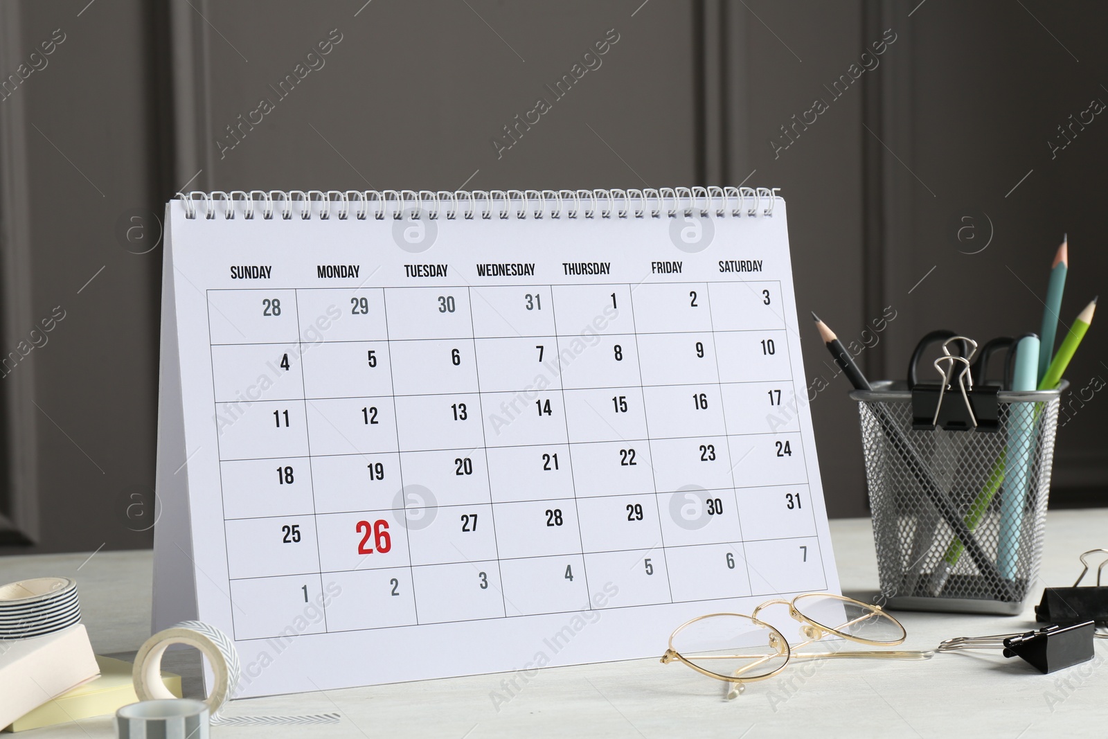 Photo of Timetable. Monthly planner, stationery and glasses on white table