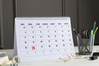 Photo of Timetable. Monthly planner, stationery and glasses on white table