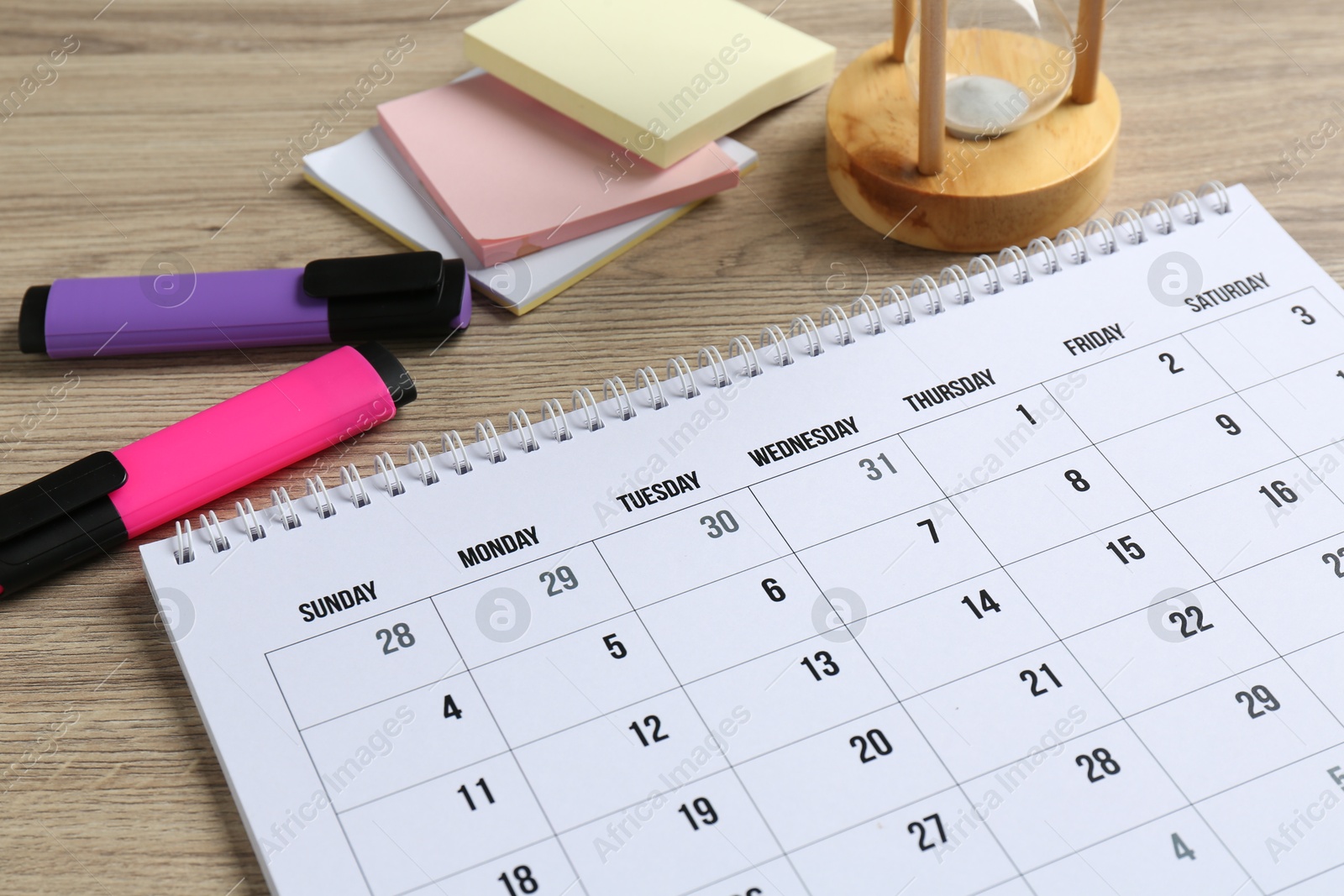 Photo of Timetable. Monthly planner and stationery on wooden table, closeup