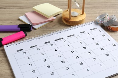 Timetable. Monthly planner and stationery on wooden table, closeup