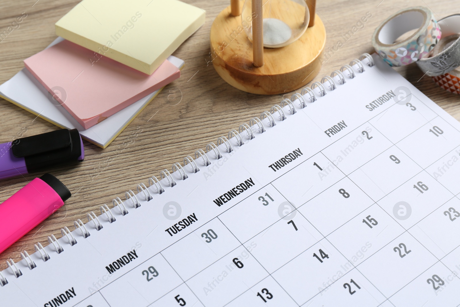 Photo of Timetable. Monthly planner and stationery on wooden table, closeup