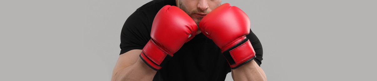 Image of Man in boxing gloves on grey background, closeup. Banner design