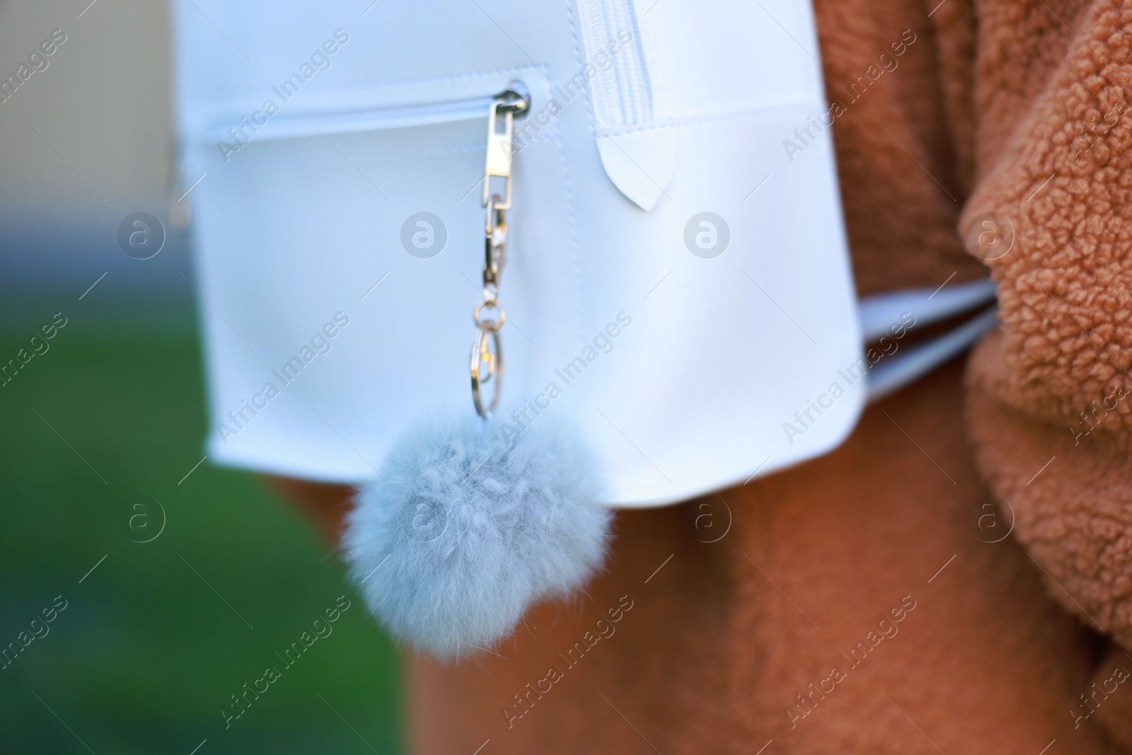 Photo of Woman with faux fur keychain on her backpack outdoors, closeup. Selective focus