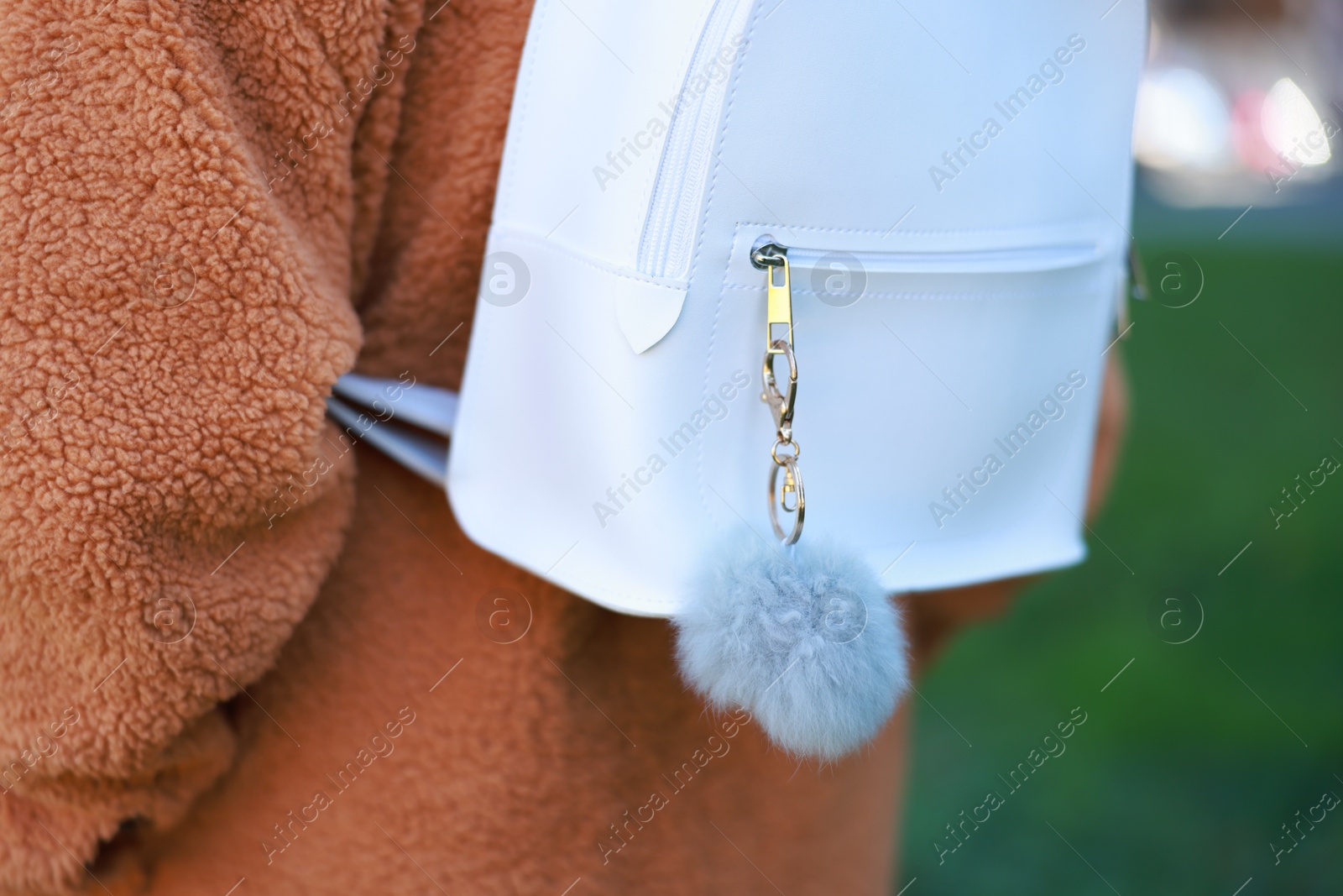 Photo of Woman with faux fur keychain on her backpack outdoors, closeup. Selective focus