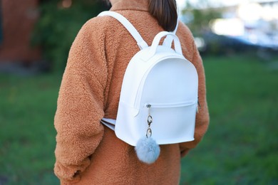 Photo of Woman with faux fur keychain on her backpack outdoors, closeup