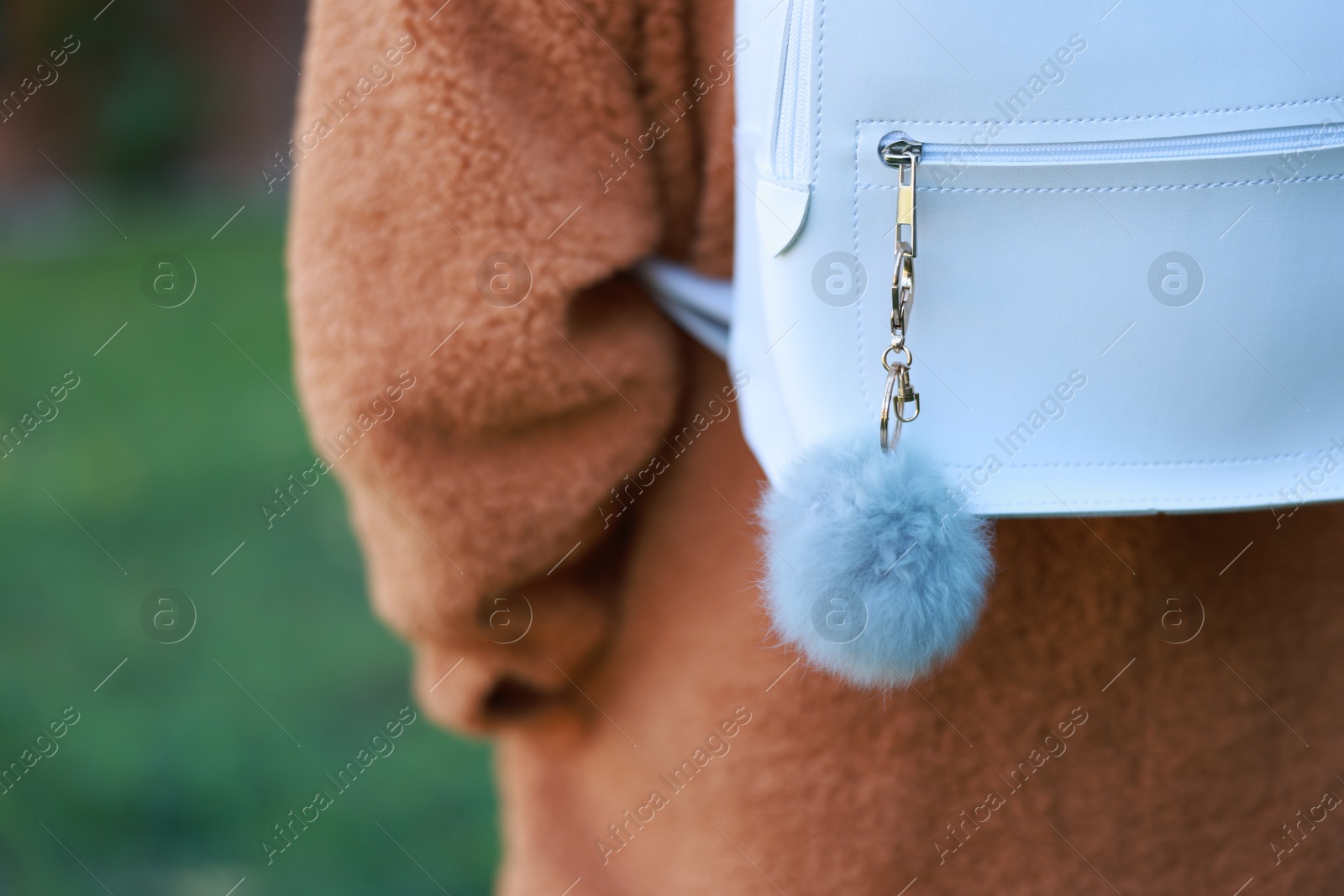 Photo of Woman with faux fur keychain on her backpack outdoors, closeup