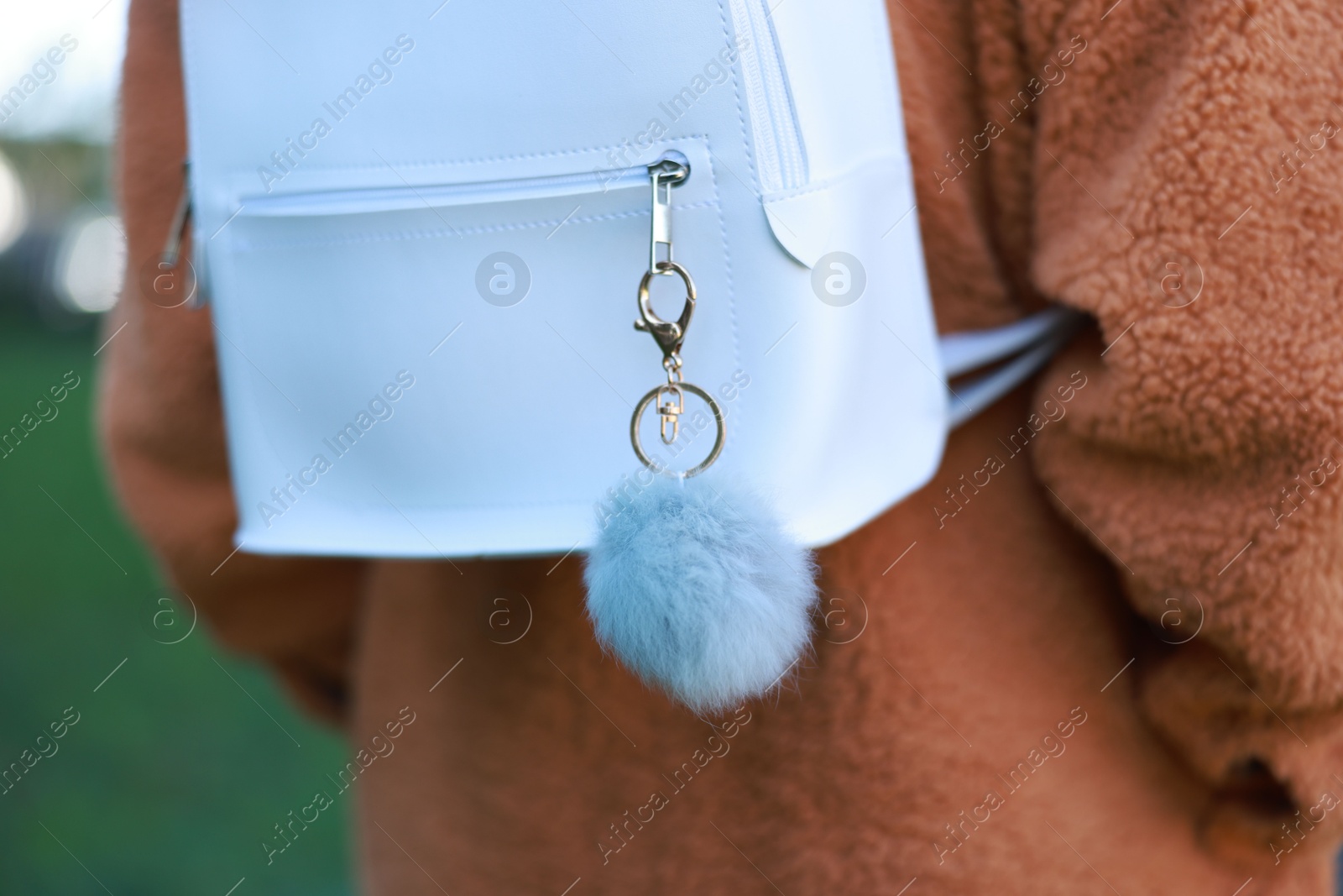 Photo of Woman with faux fur keychain on her backpack outdoors, closeup