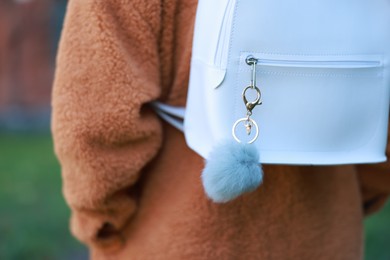 Photo of Woman with faux fur keychain on her backpack outdoors, closeup