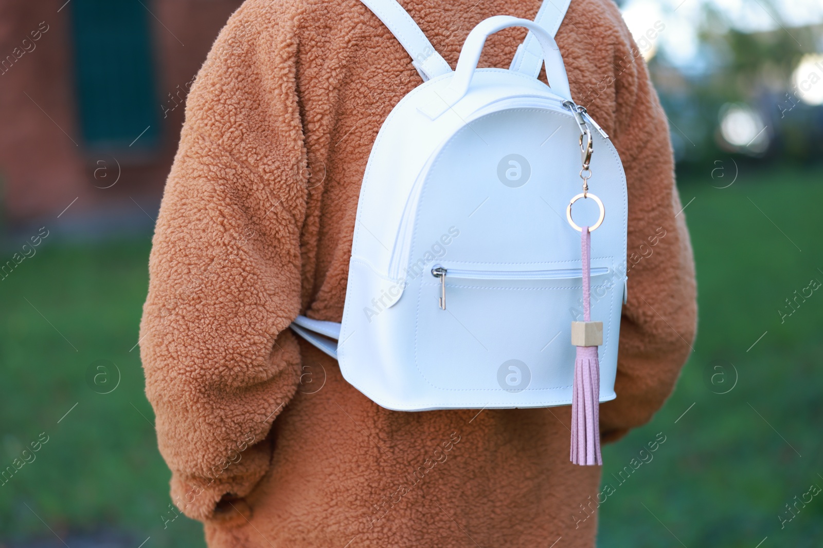 Photo of Woman with pink leather keychain on her backpack outdoors, closeup