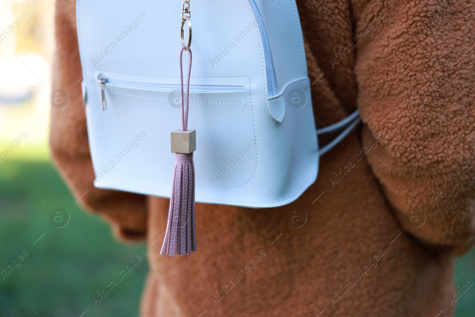 Photo of Woman with pink leather keychain on her backpack outdoors, closeup