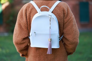 Photo of Woman with pink leather keychain on her backpack outdoors, closeup