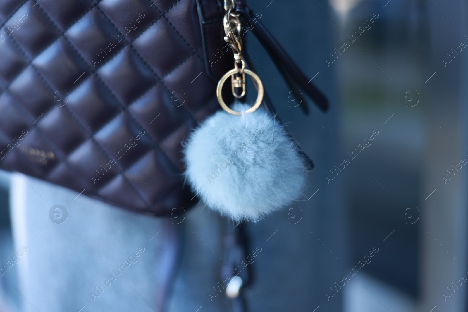 Photo of Woman with faux fur keychain on her backpack outdoors, closeup. Selective focus