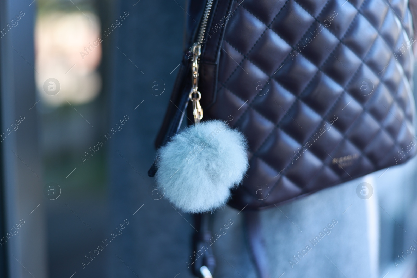 Photo of Woman with faux fur keychain on her backpack outdoors, closeup. Selective focus