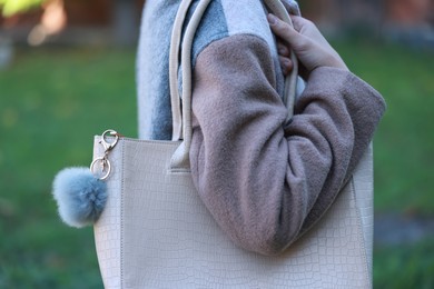 Photo of Woman with faux fur keychain on her bag outdoors, closeup