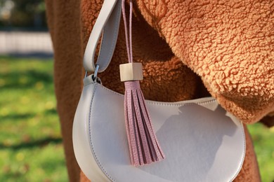 Photo of Woman with pink leather keychain on her bag outdoors, closeup