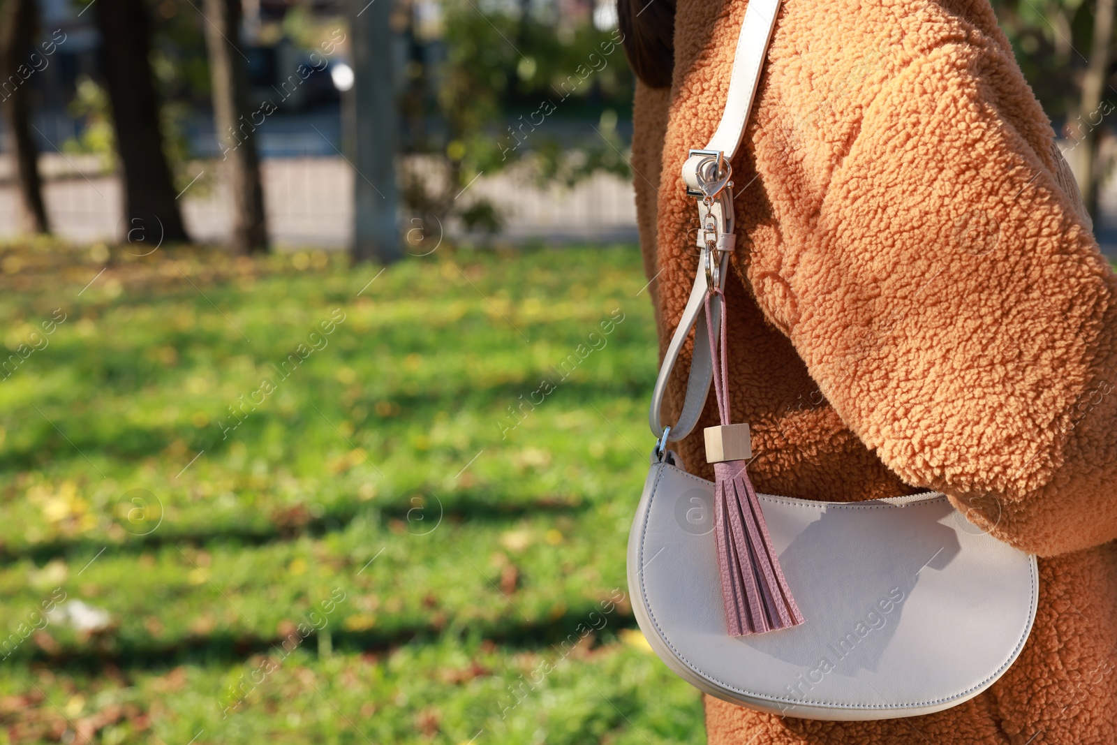 Photo of Woman with pink leather keychain on her bag outdoors, closeup. Space for text