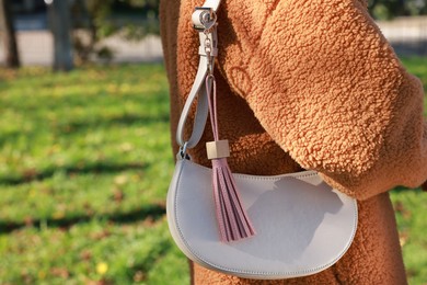 Photo of Woman with pink leather keychain on her bag outdoors, closeup