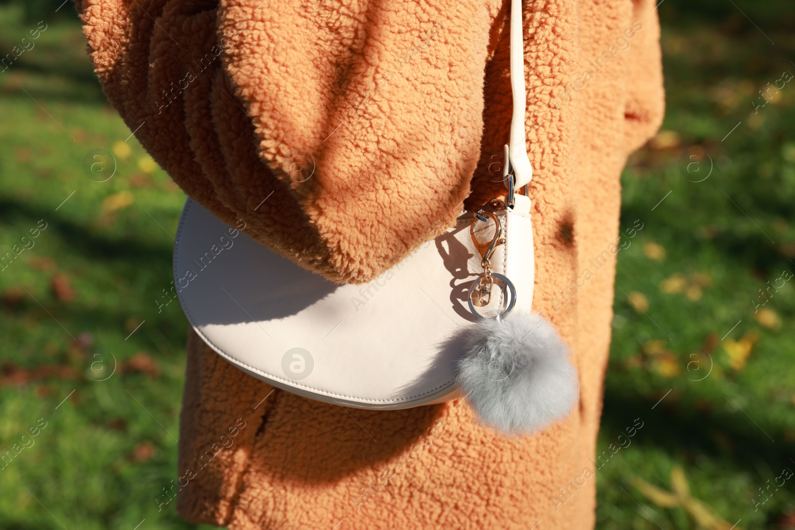 Photo of Woman with faux fur keychain on her bag outdoors, closeup