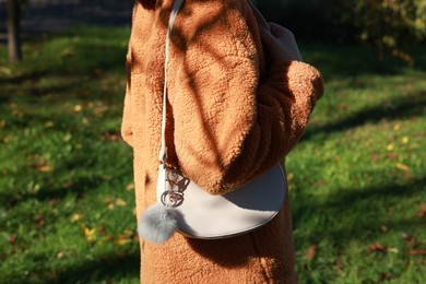 Photo of Woman with faux fur keychain on her bag outdoors, closeup