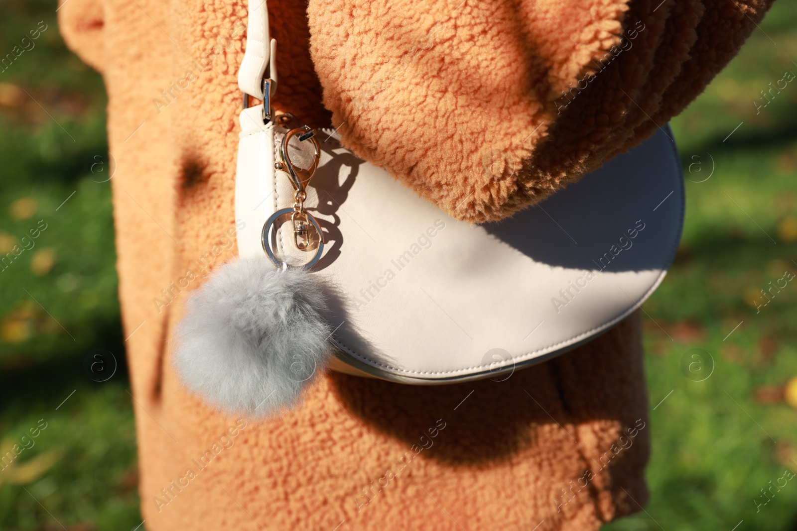 Photo of Woman with faux fur keychain on her bag outdoors, closeup