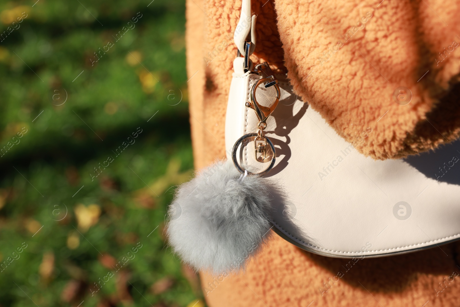 Photo of Woman with faux fur keychain on her bag outdoors, closeup