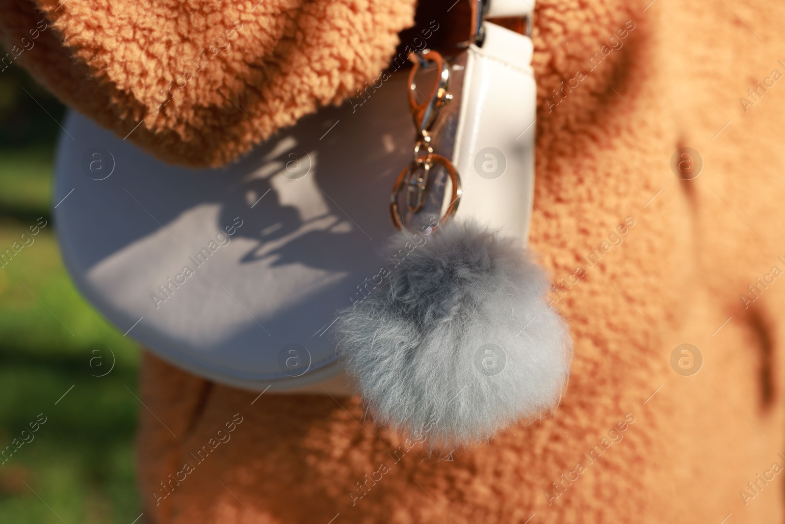 Photo of Woman with faux fur keychain on her bag outdoors, closeup