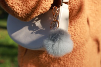 Photo of Woman with faux fur keychain on her bag outdoors, closeup