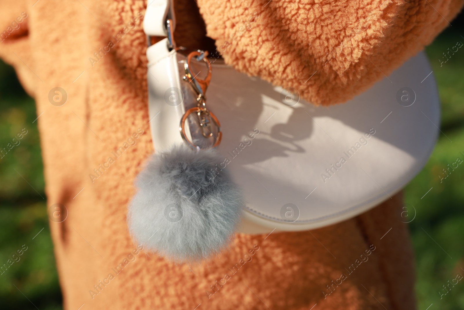 Photo of Woman with faux fur keychain on her bag outdoors, closeup