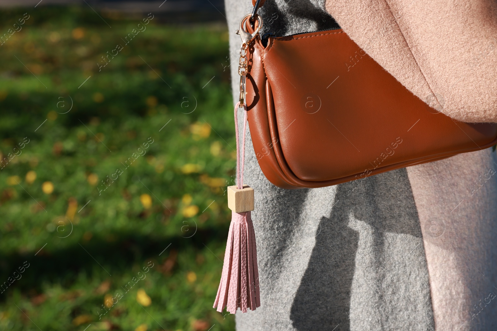 Photo of Woman with pink leather keychain on her bag outdoors, closeup. Space for text