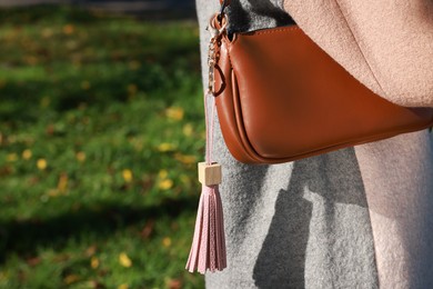 Photo of Woman with pink leather keychain on her bag outdoors, closeup. Space for text