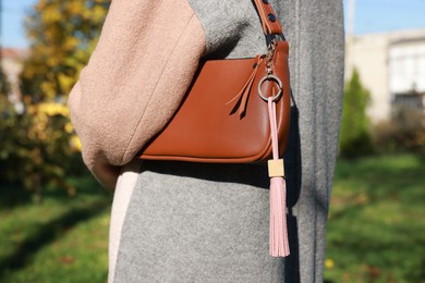 Photo of Woman with pink leather keychain on her bag outdoors, closeup