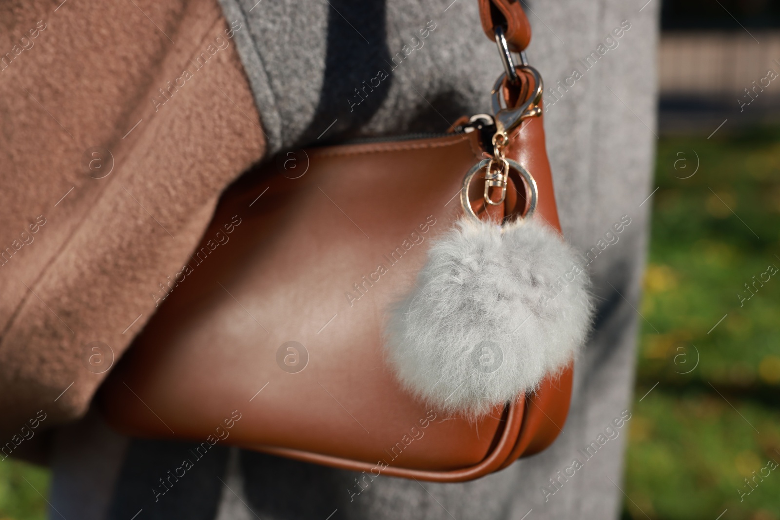 Photo of Woman with faux fur keychain on her bag outdoors, closeup