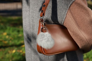 Photo of Woman with faux fur keychain on her bag outdoors, closeup