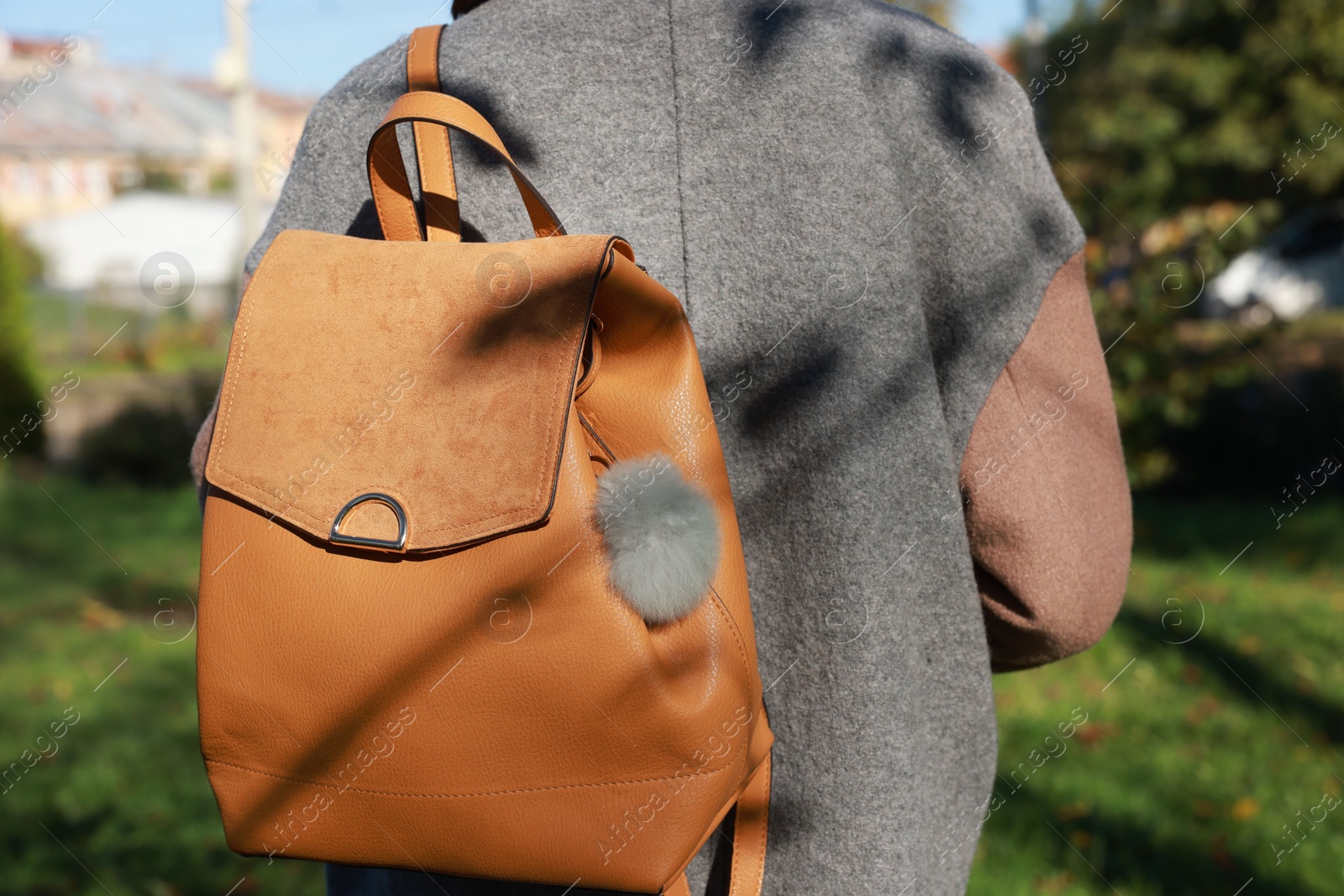 Photo of Woman with faux fur keychain on her backpack outdoors, closeup