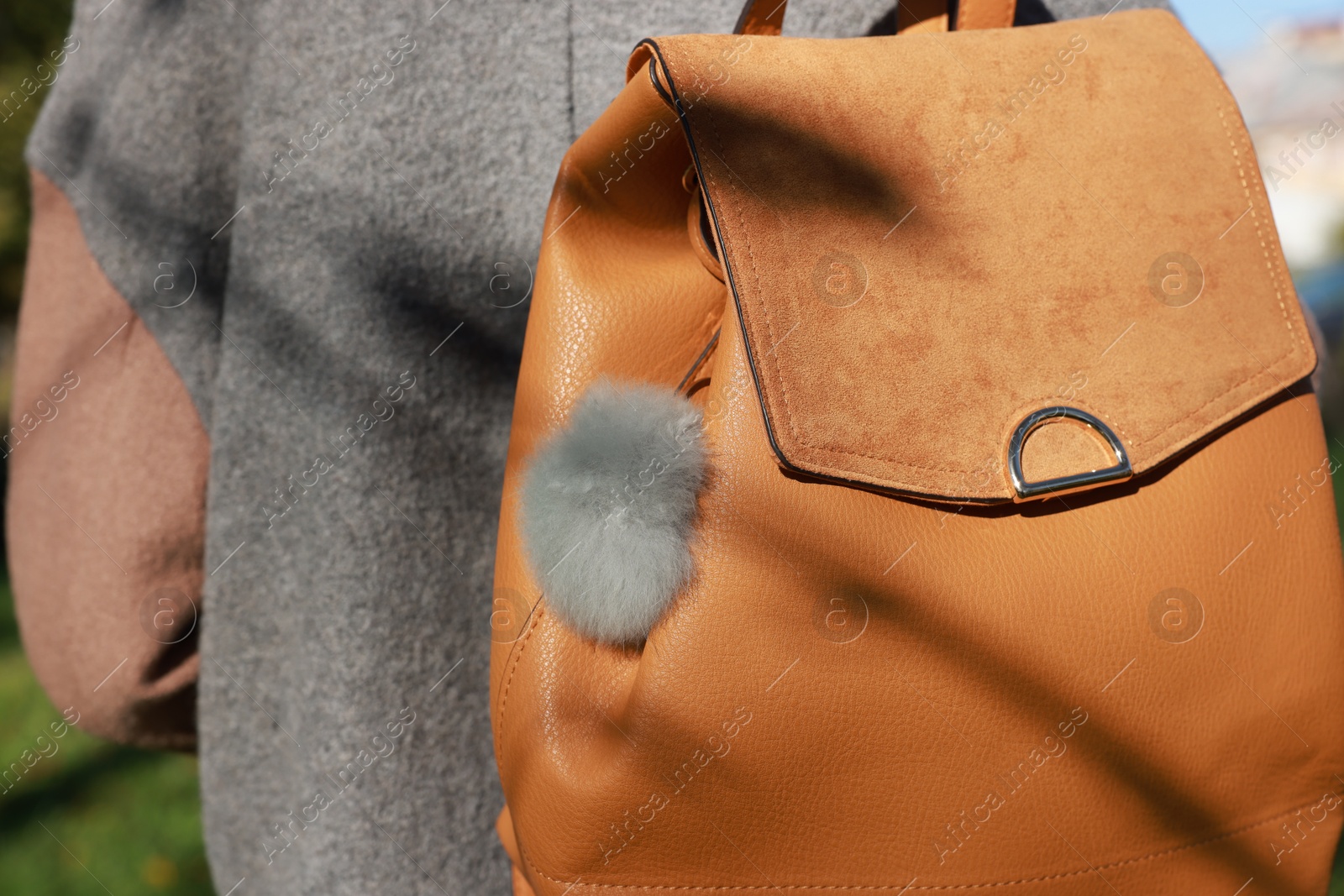 Photo of Woman with faux fur keychain on her backpack outdoors, closeup