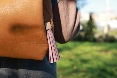 Photo of Woman with pink leather keychain on her backpack outdoors, closeup. Space for text