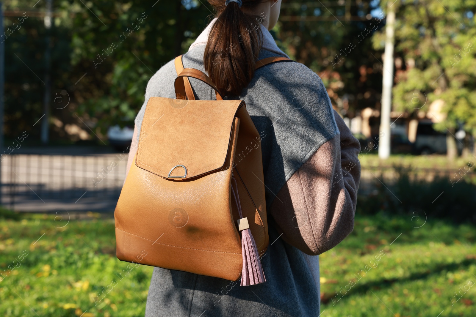 Photo of Woman with pink leather keychain on her backpack outdoors, closeup