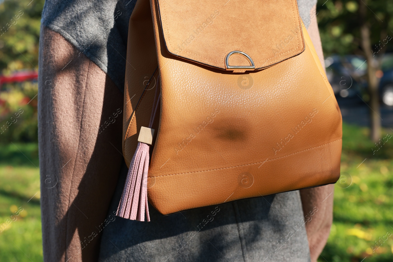 Photo of Woman with pink leather keychain on her backpack outdoors, closeup