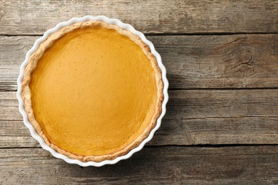 Tasty homemade pumpkin pie in baking dish on wooden table, top view. Space for text