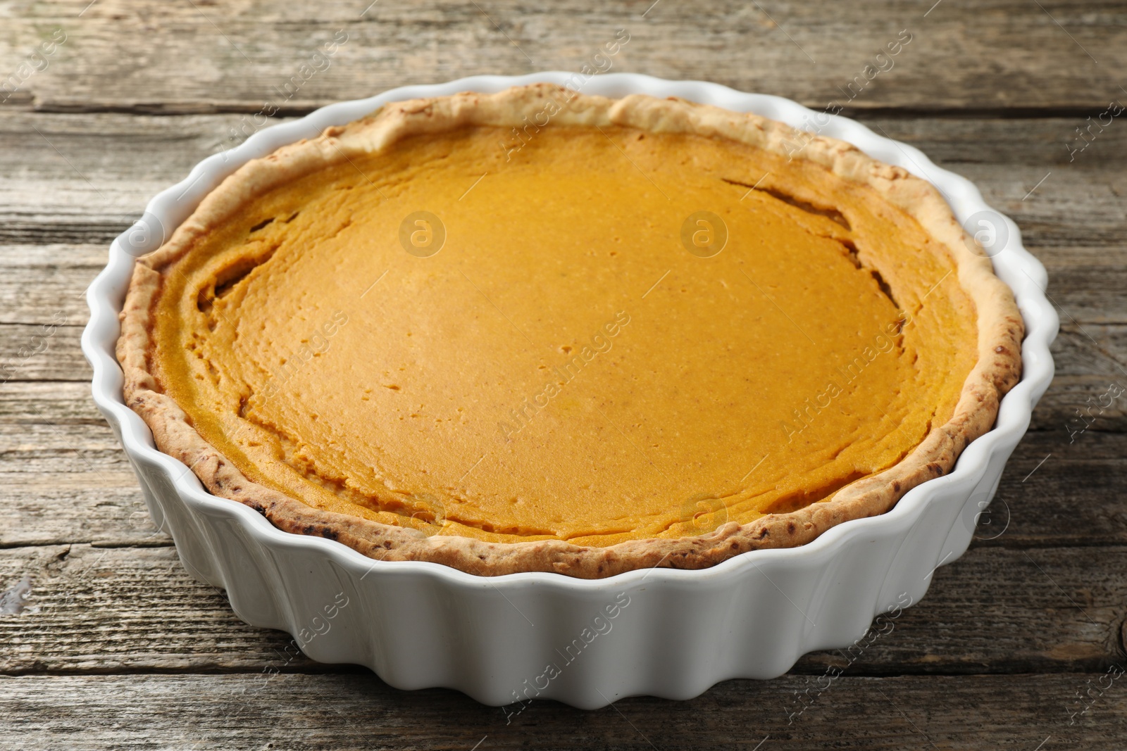 Photo of Tasty homemade pumpkin pie in baking dish on wooden table, closeup