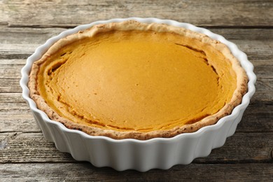 Photo of Tasty homemade pumpkin pie in baking dish on wooden table, closeup