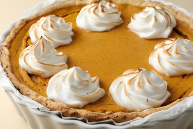 Photo of Tasty homemade pumpkin pie in baking dish on beige table, closeup