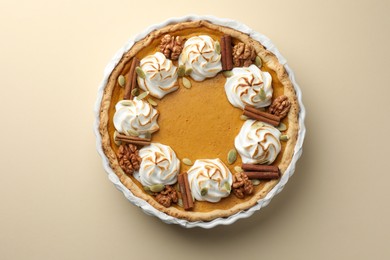 Tasty homemade pumpkin pie in baking dish on beige table, top view