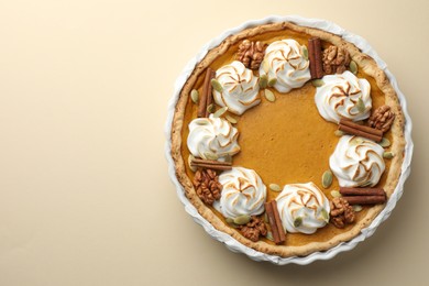 Photo of Tasty homemade pumpkin pie in baking dish on beige table, top view. Space for text