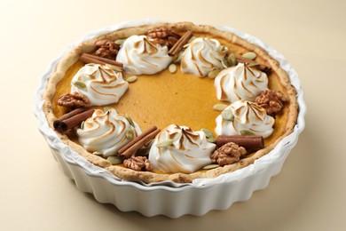 Photo of Tasty homemade pumpkin pie in baking dish on beige table, closeup