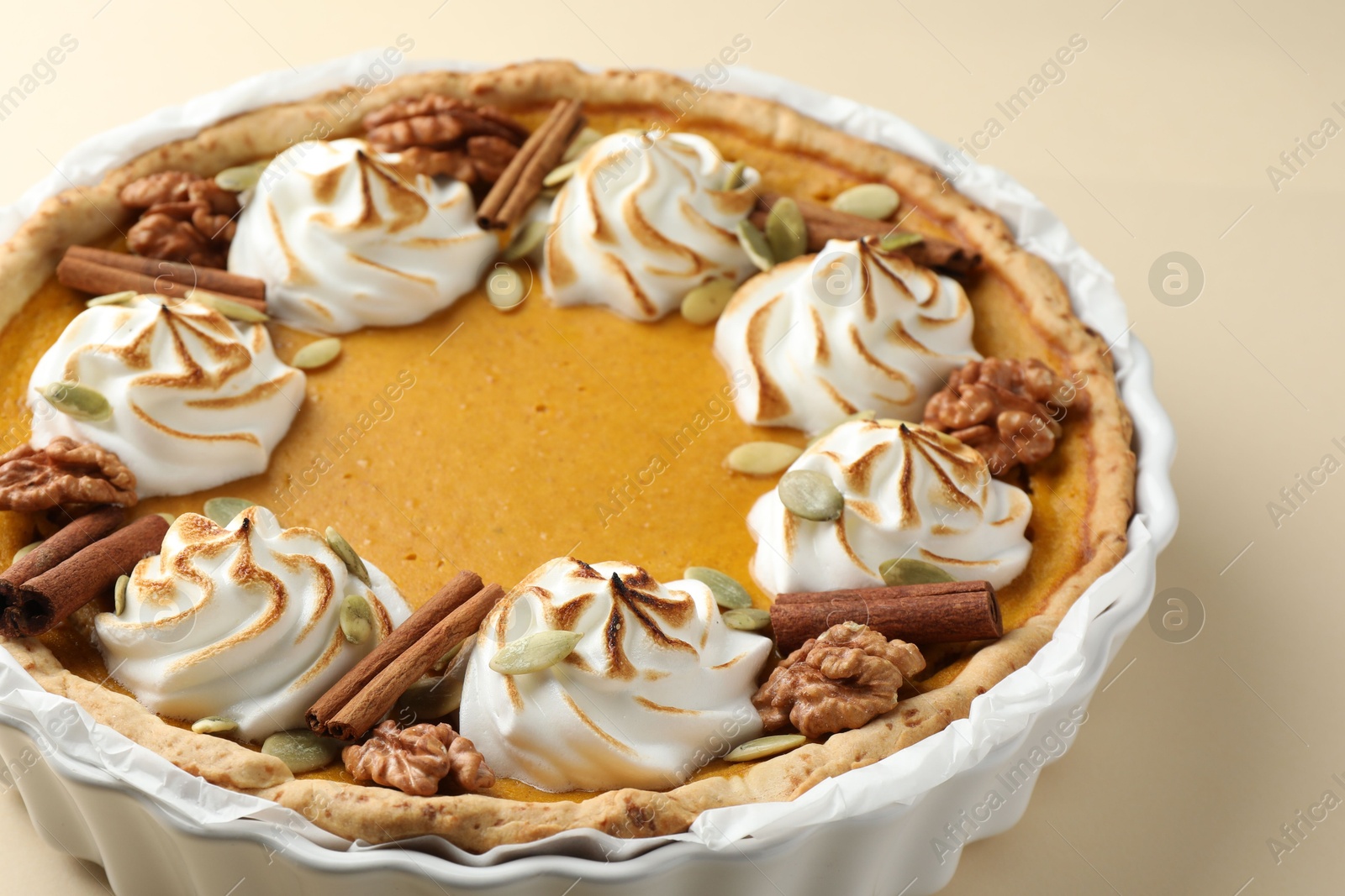 Photo of Tasty homemade pumpkin pie in baking dish on beige table, closeup