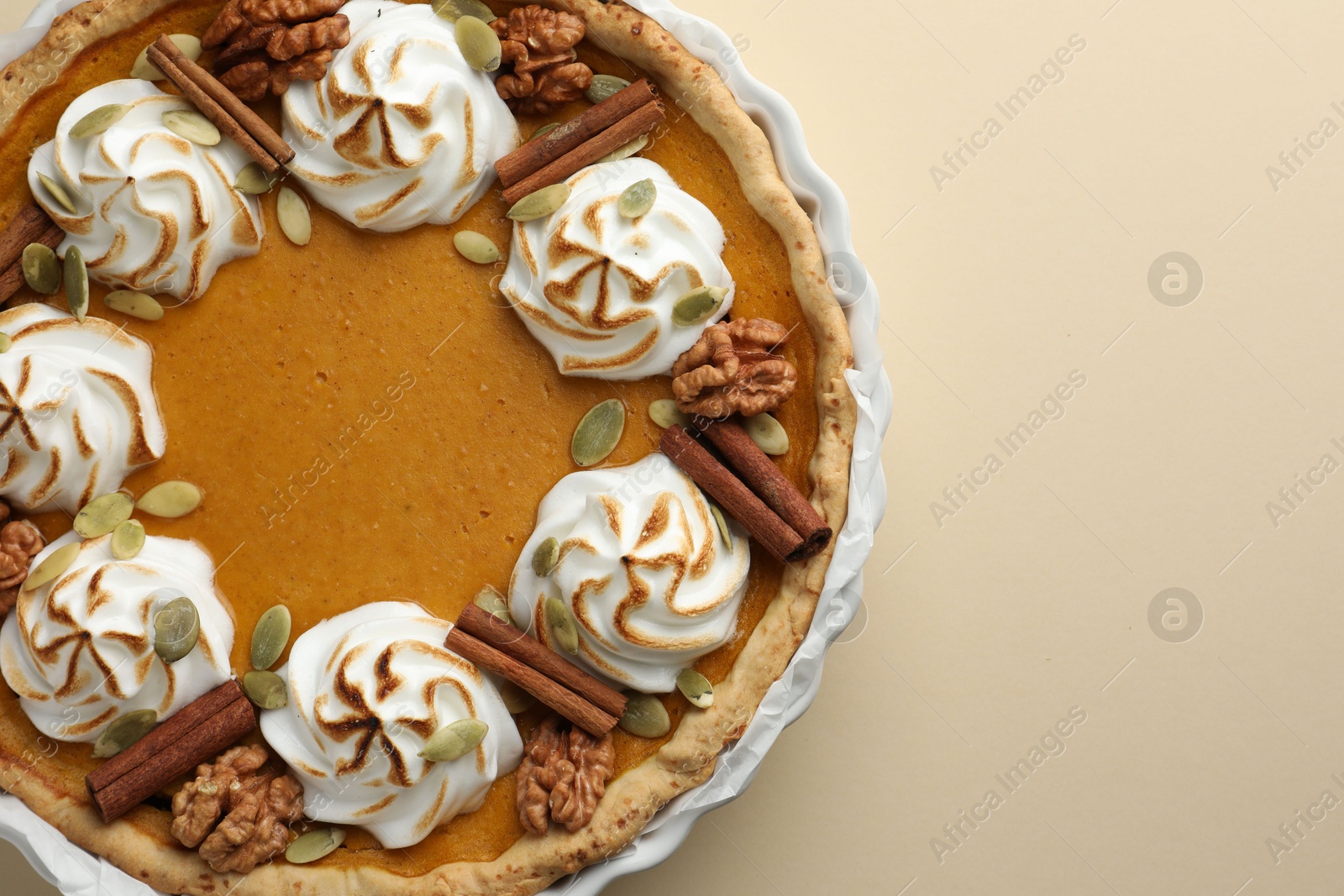 Photo of Tasty homemade pumpkin pie in baking dish on beige table, top view. Space for text