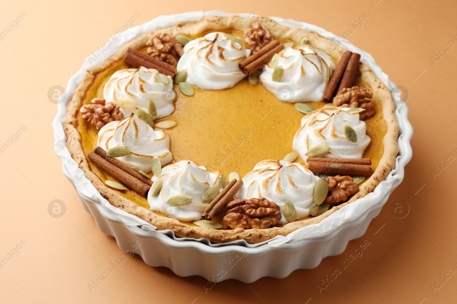 Photo of Delicious homemade pumpkin pie in baking dish on orange table, closeup